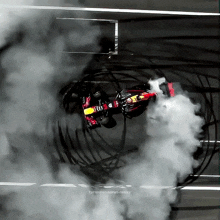 a picture of a red bull race car with smoke coming out of the tires