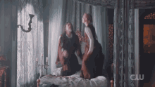 a man and a woman are sitting on a bed with a cw logo on the bottom right
