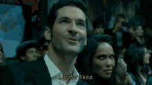 a man in a suit says lucifer likes in front of a woman