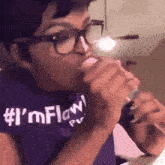 a woman wearing glasses and a purple shirt that says i 'm flow on it