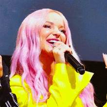 a woman with pink hair is holding a microphone in her hand and smiling .