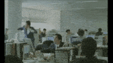 a man in a suit and tie is standing in an office surrounded by other people