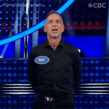a man with a name tag that says billy is standing on a stage .