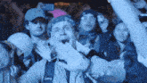 a man with a bandana on his head is screaming in front of a crowd
