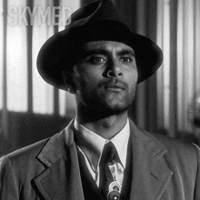 a black and white photo of a man in a suit and hat with the word skymed behind him