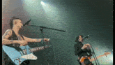 a man and a woman playing guitars and singing into microphones on a stage