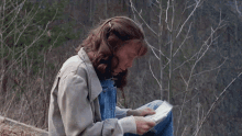 a woman sits on a rock reading a book