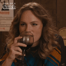 a woman is drinking a glass of wine with the words son of a bitch written above her