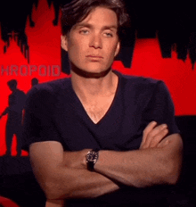 a man stands with his arms crossed in front of a red background with the word hropoid on it