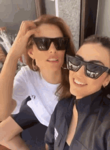 two women wearing sunglasses and a white shirt that says ex