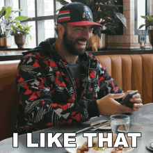 a man is sitting at a table with a plate of food and a glass of water and says " i like that "