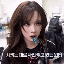 a girl with a blue candy in her mouth and a foreign language behind her