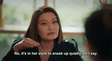 a woman in a black jacket is talking to another woman while sitting at a table in front of a window .