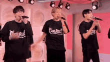 a group of men are singing into microphones on a stage .