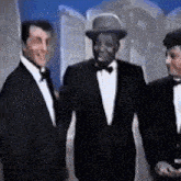 three men in tuxedos and bow ties are standing next to each other and smiling .