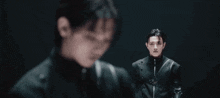 a man in a black suit is standing next to another man in a black suit in a dark room .