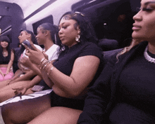 a group of women are sitting on a couch and one of them is looking at her phone