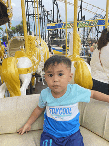 a young boy wearing a blue shirt that says stay cool