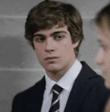 a young man wearing a suit and tie is looking at the camera