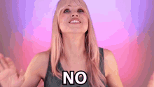 a woman is smiling and saying no with her hands out