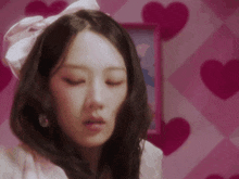 a close up of a woman 's face with her eyes closed in a room with hearts on the wall .