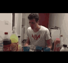 a man wearing a shirt that says nm is standing in front of a coca cola bottle