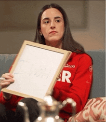 a woman is sitting on a couch holding a white board with the word i won written on it