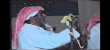 a man is singing into a microphone while wearing a red and white head scarf