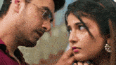 a man wearing glasses is touching a woman 's neck