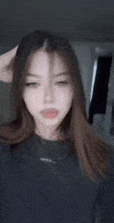 a woman with long brown hair is wearing a black shirt that says ' a ' on it