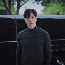 a young man in a black shirt stands in front of a van