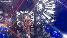 a man is walking on a stage in front of a large screen with a lot of lights .