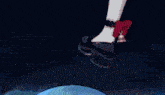 a close up of a person 's foot with a red bow on it standing on a blue surface .