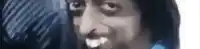 a close up of a man 's face with his mouth open and a blue shirt on .