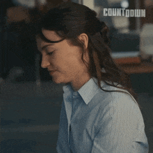 a woman in a blue striped shirt is sitting in front of a countdown sign