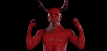 a close up of a demon 's face with horns on a black background .