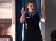 a stewardess stands in front of a blue curtain