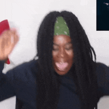 a woman with dreadlocks is making a funny face while wearing a bandana .