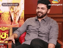 a man with a beard is sitting in a chair and smiling while talking to someone .