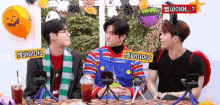 three young men are sitting at a table talking to each other .