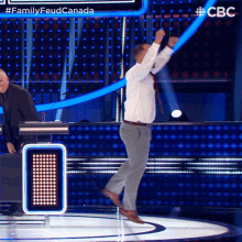 a man in a white shirt and tie is dancing on a stage in front of a sign that says family feud canada