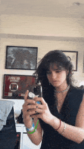 a woman taking a picture of herself in front of a framed picture that says j.k.b.a.i.a