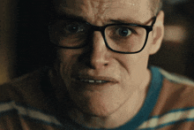 a close up of a man 's face with glasses on