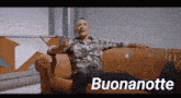 a man is sitting on a couch with the word buonanotte written below him