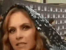 a close up of a woman 's face with a scarf around her head and a building in the background .