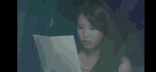 a woman is sitting in a car reading a piece of paper in the dark .