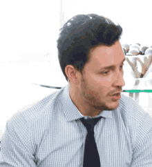 a man wearing a striped shirt and tie looks to the side