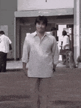 a man in a white shirt and khaki pants is walking down the street