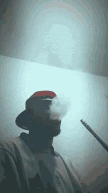 a man in a red hat is smoking a hookah with smoke coming out of his mouth