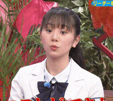 a girl in a white jacket and black bow tie is sitting in front of a sign that says ' league '